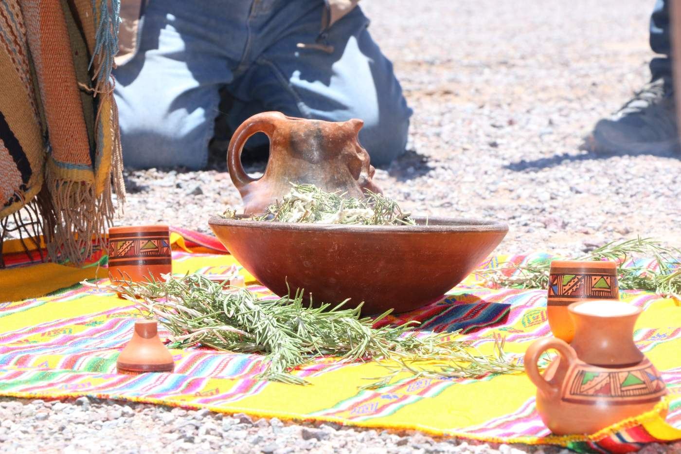 Ofrenda ceremonial con hojas y cántaros sobre un tejido